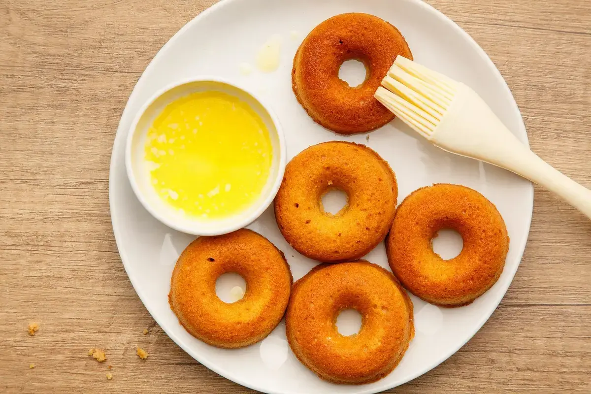 Brushing baked donuts with melted butter